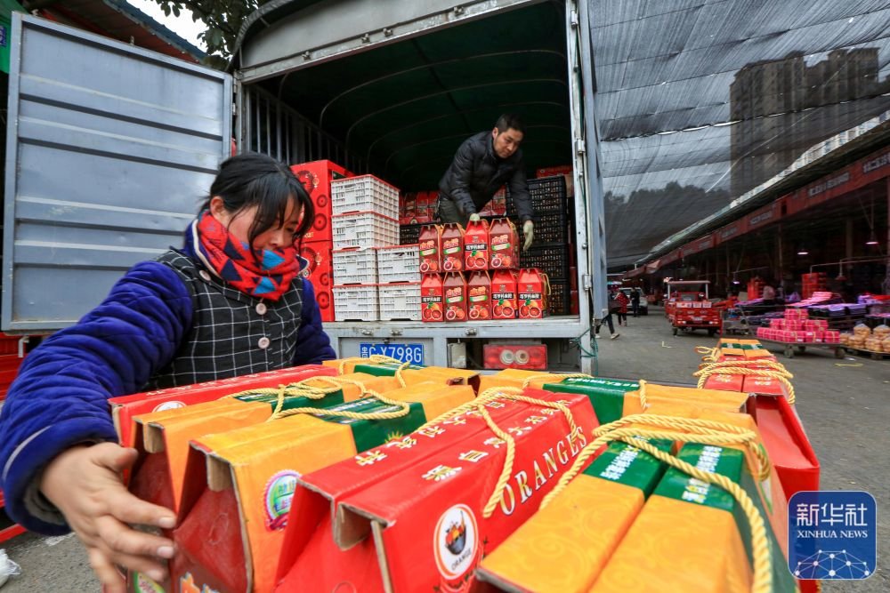 1月21日,工人在贵州省遵义市播州区龙坑街道农产品批发市场里搬运新鲜水果。新华社发(李仁军摄)