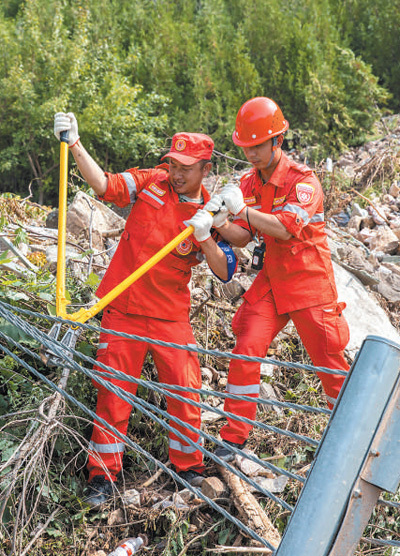 8月3日，中国安能集团组织党员突击队前往北京市门头沟区进行道路抢通工作。图为两名队员在234国道清理障碍。　　
