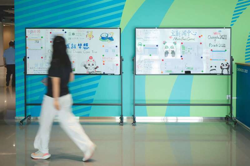 主媒体中心的工作人员日常将通过手绘的方式将赛事信息和媒体服务信息更新在白板上。汪龙华/摄