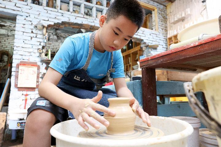 小学生在福建省福州市长乐区吴村村陶源里文创街区学习制作陶艺作品