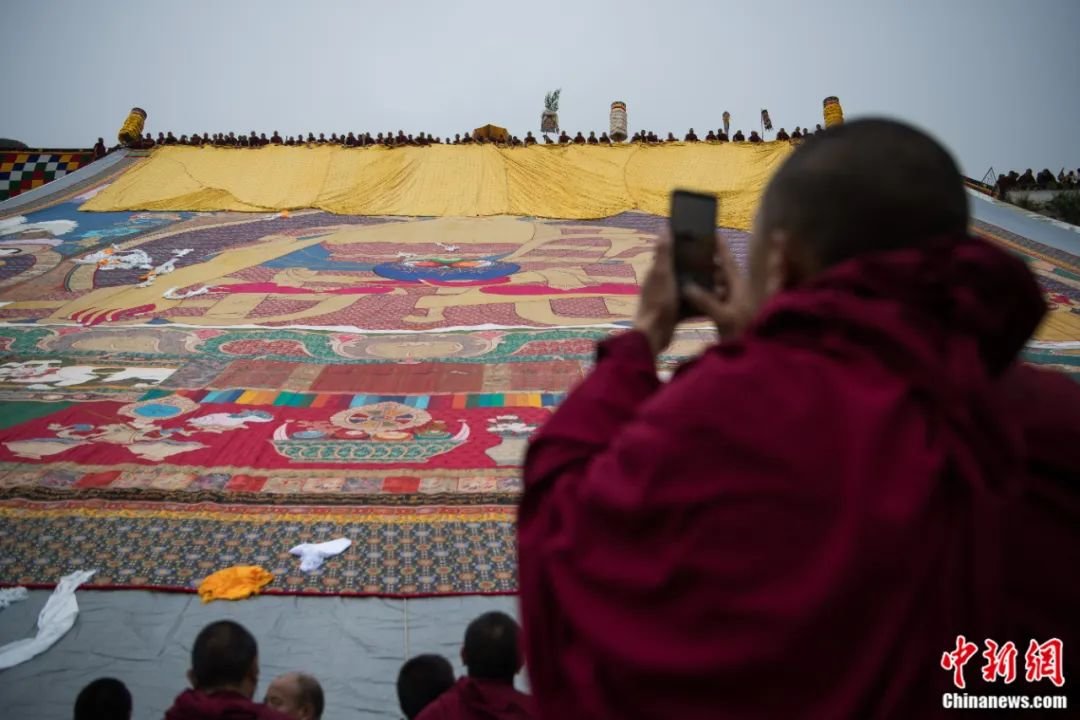 西藏拉萨哲蚌寺举行展佛活动，僧人用手机记录。何蓬磊 摄