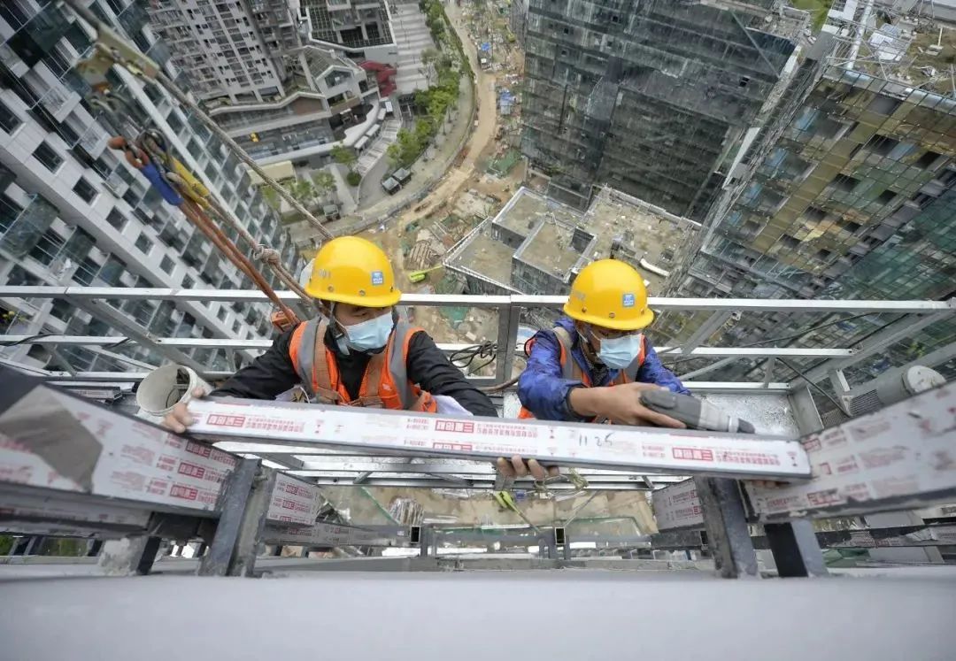 ▲2022年4月30日,工人在四川成都某工地为一栋超高层建筑安装幕墙。(图源:新华社)