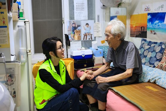 图为金建希在中秋节前夕的13日下午访问首尔站棚户区，正在赠送中秋礼物套装，与老人进行对话。图源：韩媒