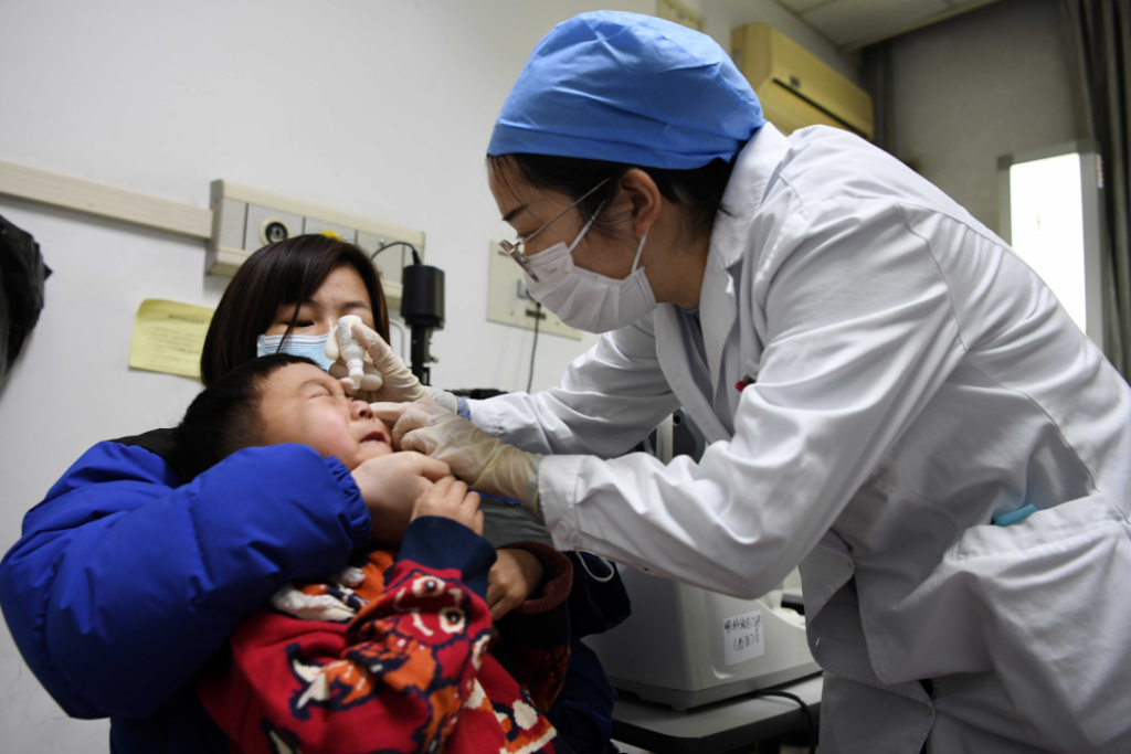 医生为一位眼睛受伤的小朋友滴眼药水。