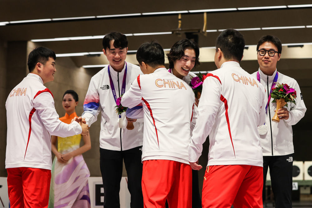9月25日，冠军中国队选手李越宏（左三）、刘杨攀（左一）、王鑫杰（右二）在男子25米手枪速射团体颁奖仪式上向亚军韩国队致意。