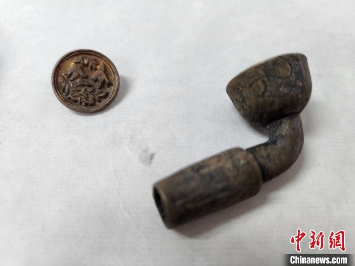 带图案的金色纽扣、刻有鱼纹的烟斗。 赵晓 摄