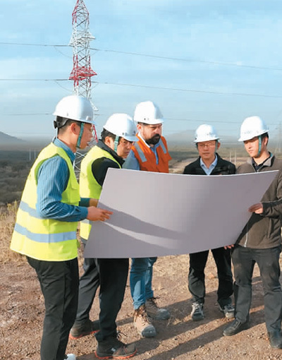 在智首个高压直流输电项目现场，甘运良（右二）带领团队与当地技术专家开展现场调研。