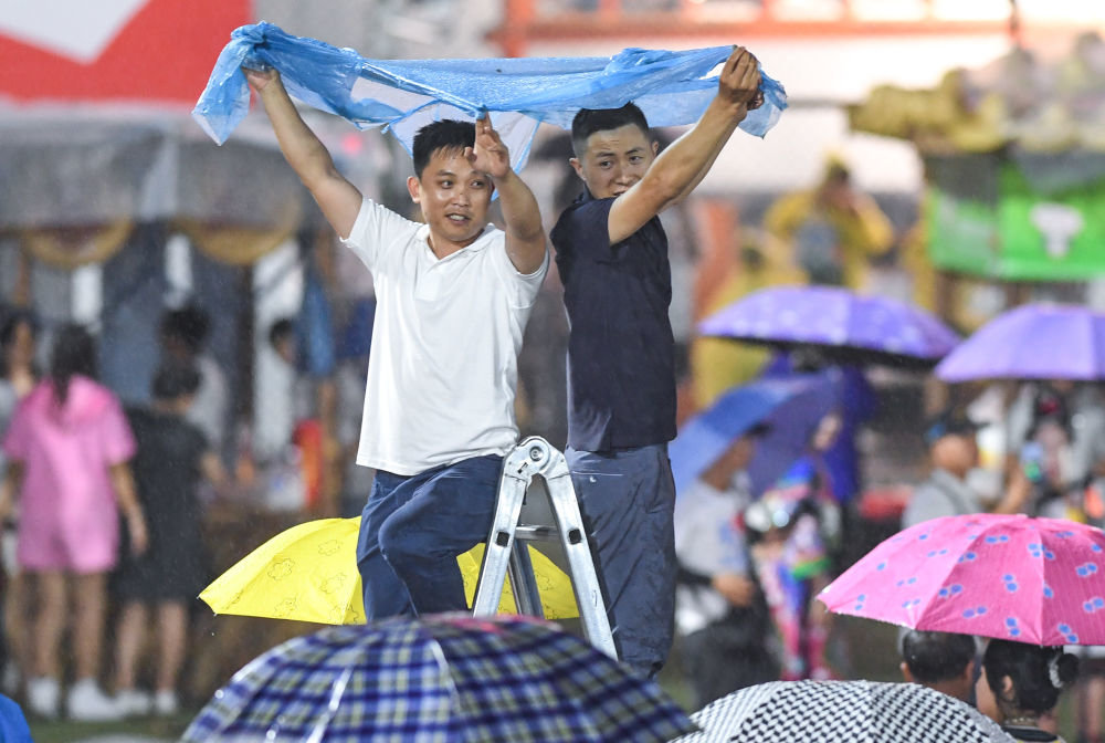 ↑6月23日,观众冒雨观看球赛。新华社记者 杨文斌 摄