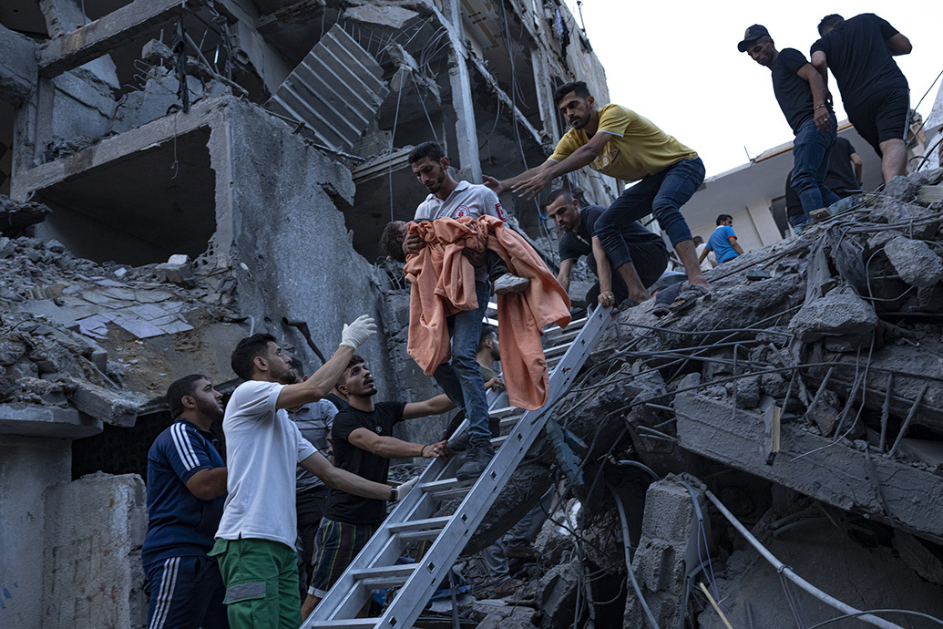 当地时间2023年10月10日，加沙城，以色列空袭后，人们从被毁住宅楼的废墟中救出一名小女孩。