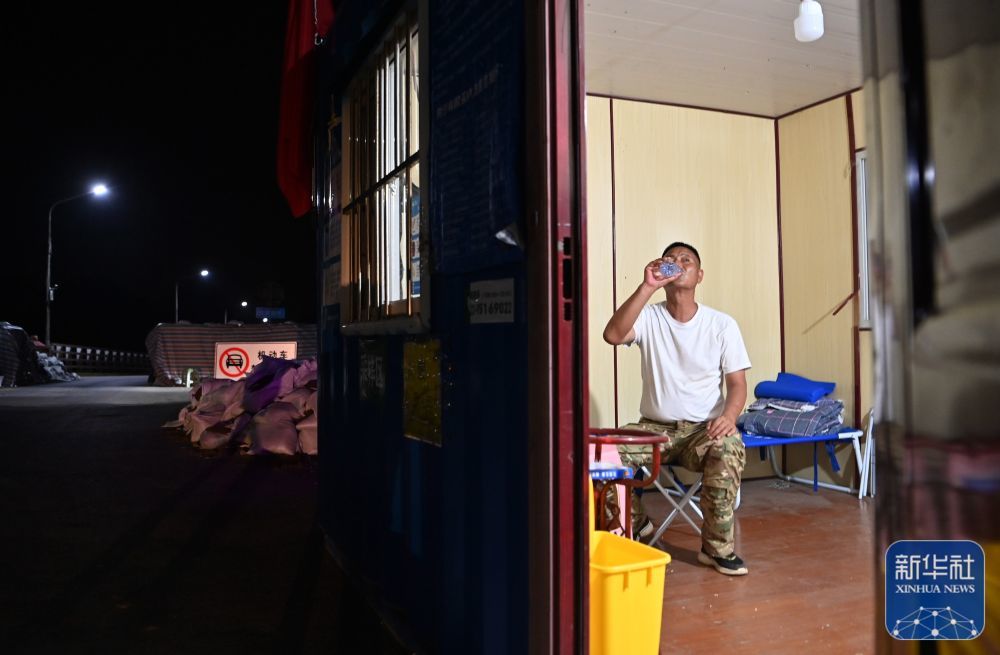 郝庆水在临时板房内喝水休息（8月3日摄）。