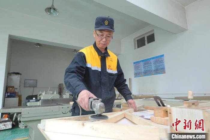图为梁军使用角磨机打磨木头,让木制品更加平整光滑。 周悦翔 摄