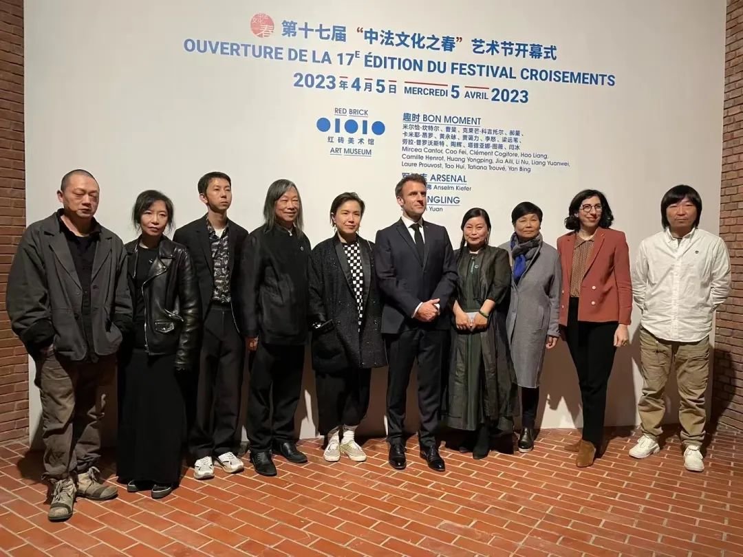 ▲ 在红砖美术馆“趣时“展览现场,法兰西共和国埃马纽埃尔·马克龙(中)、法国文化部长阿卜杜勒·玛拉克(Rima Abdul Malak),右二)与红砖美术馆创始人闫士杰(左四)、曹梅(右四)夫妇及艺术家曹斐(左五)、梁远苇(左二)、陶辉(左三)、李怒(左一)、闫冰(右一)合影,图片来源:孙文杰