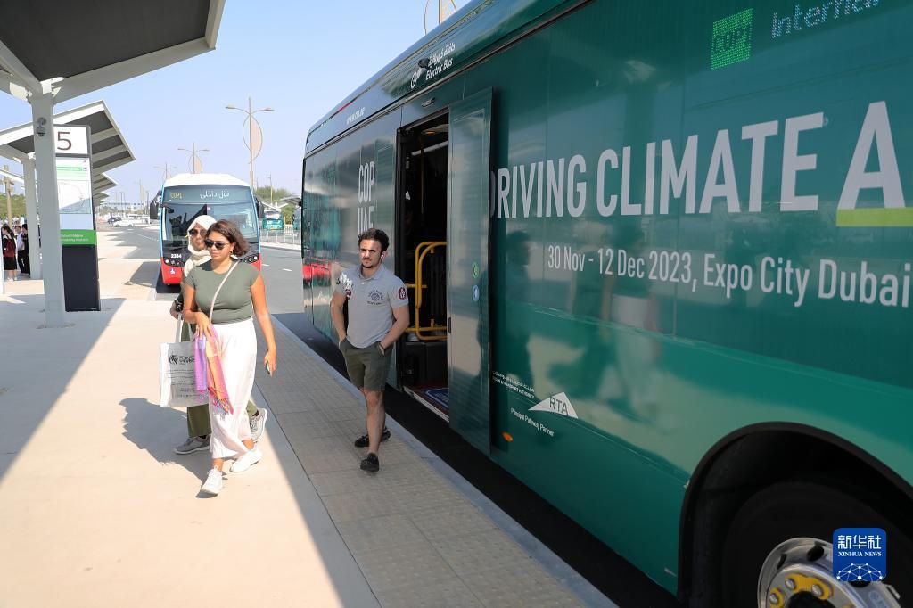 12月3日，在联合国气候变化迪拜大会的摆渡车停靠点，人们从中国苏州金龙公司的海格电动巴士下车。新华社记者 王东震 摄