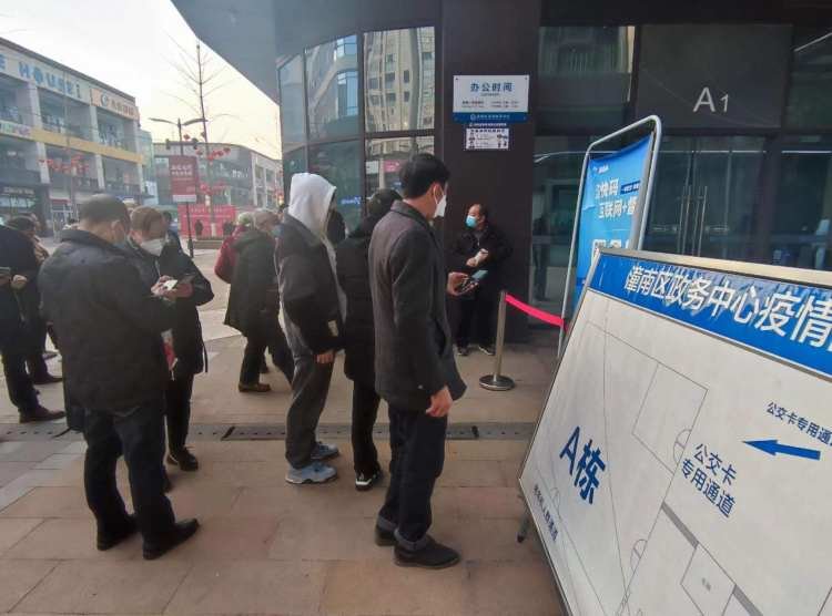 ▲行政服务中心引导员在入口引导办理业务的市民