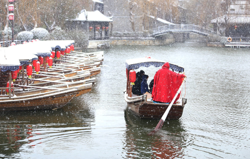 1月14日,在山东省枣庄市台儿庄古城,游客乘船观赏雪景。 新华社发(张严新 摄)
