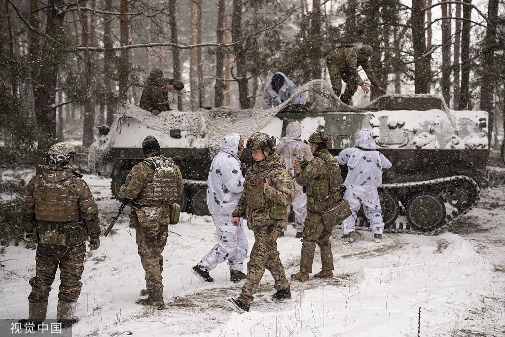 2月18日，乌克兰库皮扬斯克，即将轮换回前线位置的乌克兰军人站在装甲运输车旁。（视觉中国）