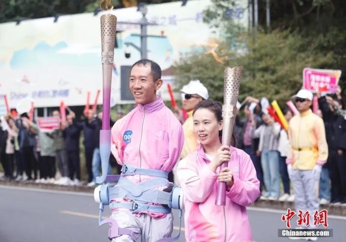10月20日,杭州第4届亚洲残疾人运动会火炬传递富阳站在浙江省杭州市富阳区启动。图为第4棒火炬手彭超(左)与第5棒火炬手李伟儿(右)与火炬合影。中新社记者 肖健 摄