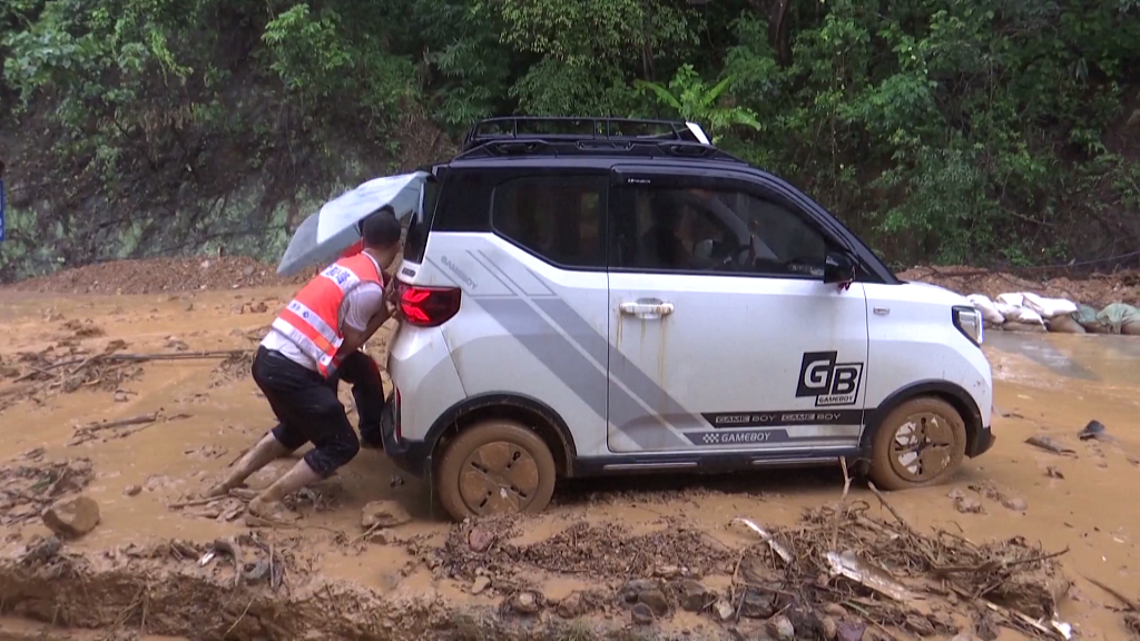 2023年6月25日，广西贺州，暴雨过后，人们把汽车从泥里推出来。（视频截图）