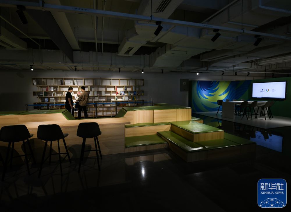 ↑7月13日,在成都大运会主媒体中心的休闲娱乐区,两名媒体记者在翻阅图书。 新华社记者 王曦 摄