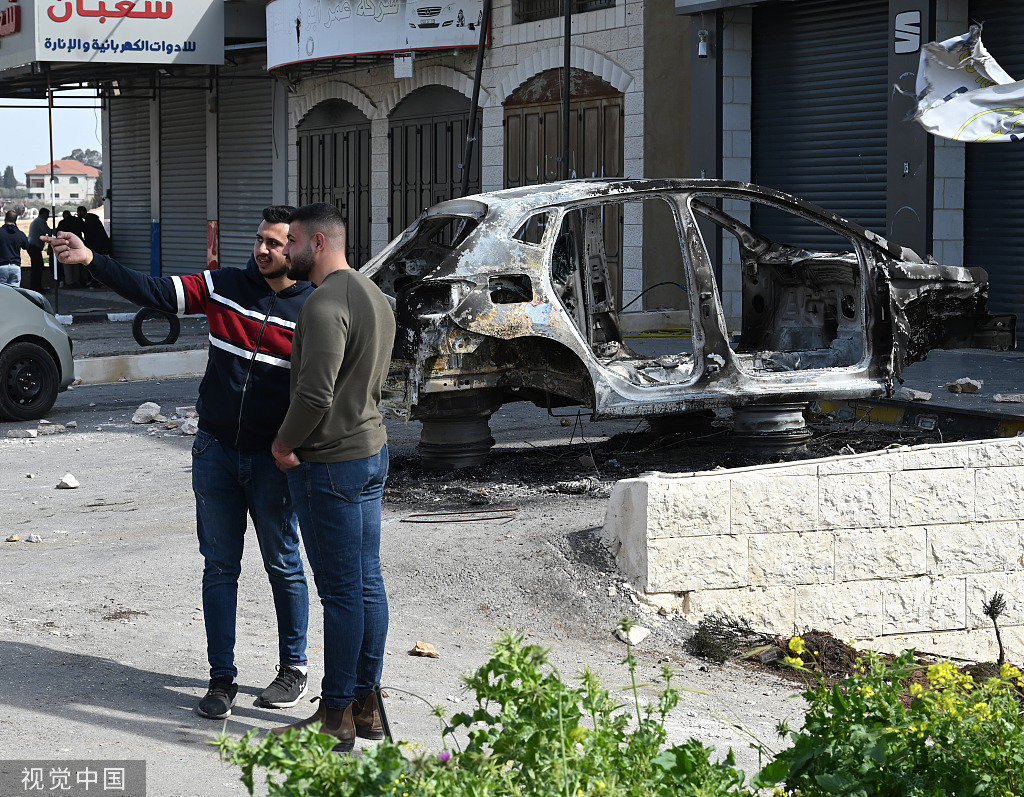 当地时间2023年2月27日，约旦河西岸哈瓦拉，两名以色列兄弟被一名巴勒斯坦枪手杀害，巴勒斯坦人在一辆被以色列定居者焚烧的汽车旁讲话。
