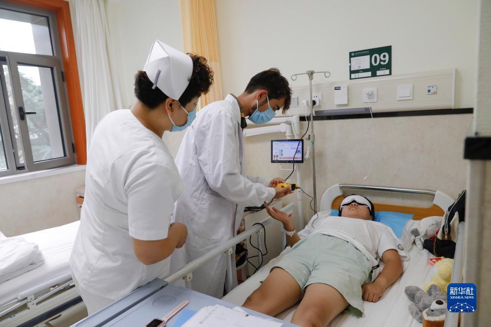 甘肃中医药大学针灸推拿专业的塔吉克斯坦留学生纪明哲（中）在临床实习中为患者进行直流电离子导入操作（7月27日摄）。新华社记者 方欣 摄
