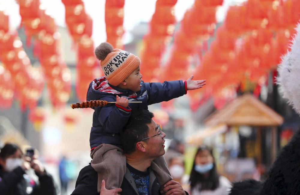 ↑1月25日，家长带着孩子在山东省枣庄市薛城区铁道游击队景区逛庙会。新华社发（李志军 摄）