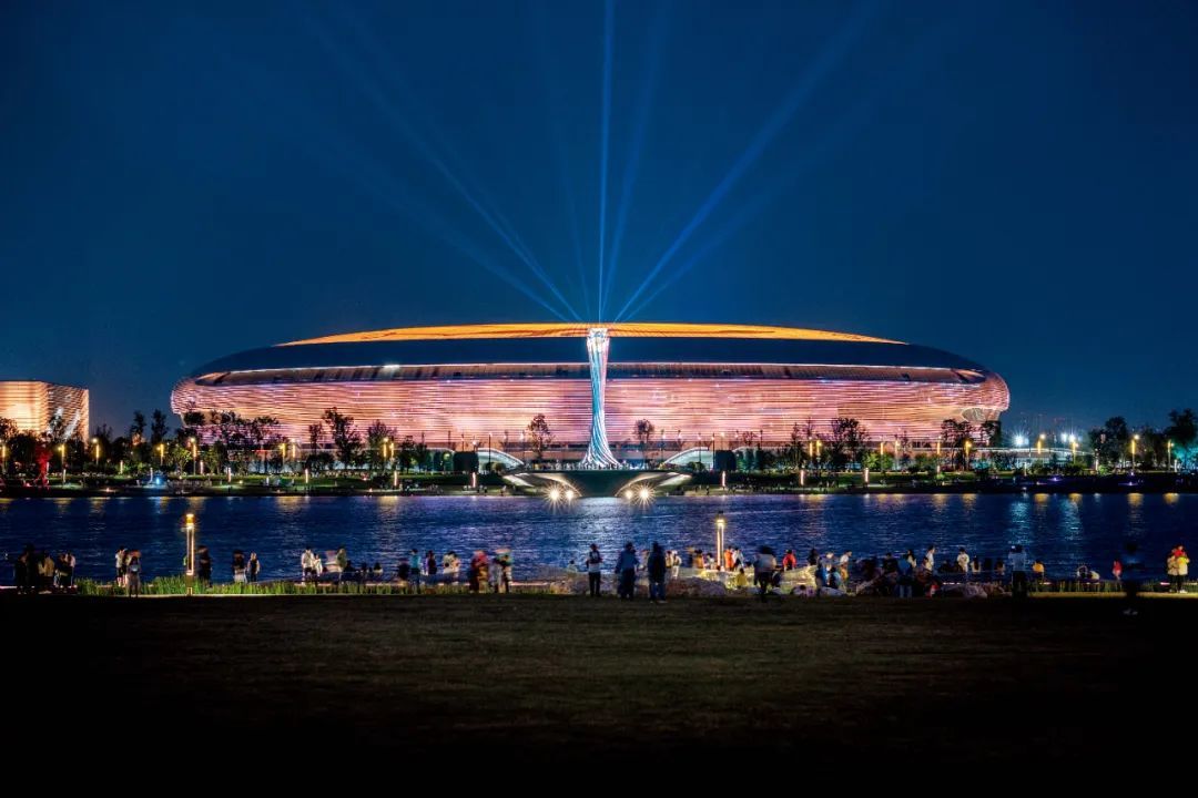 成都东安湖体育公园，人们在湖边欣赏大运会主场馆夜景。图/视觉中国