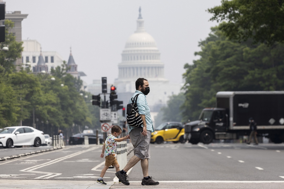 当地时间2023年6月29日，美国华盛顿，受到加拿大森林大火产生的烟霾持续影响，当地空气质量较差。家长和孩子戴着口罩出行。