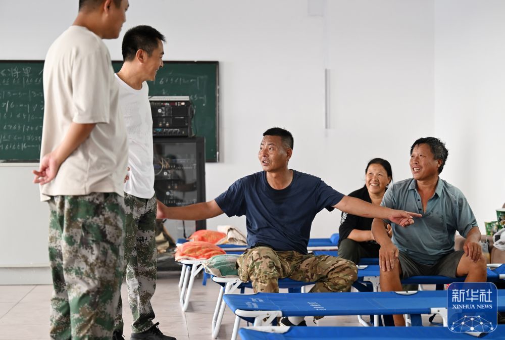 8月4日，郝庆水（左三）和村干部一起在第六埠村安置点和群众交流。