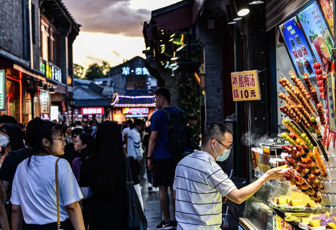 6月10日，人们在北京什刹海附近的烟袋斜街买小吃。 新华社记者 陈钟昊 摄
