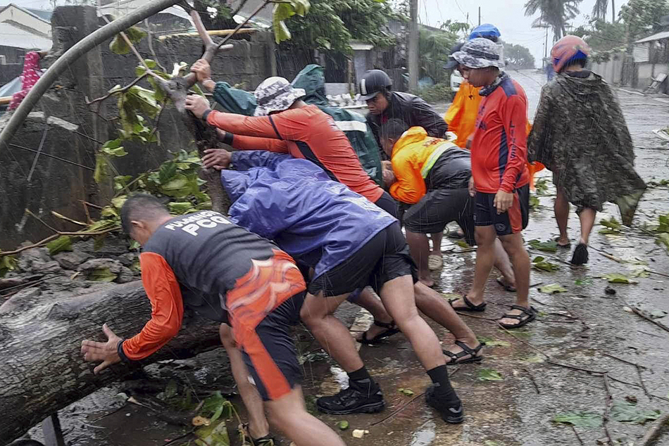 当地时间2023年7月26日,菲律宾卡加延省,海岸警卫队人员正在清理一条道路上被台风“杜苏芮”刮倒的树木。