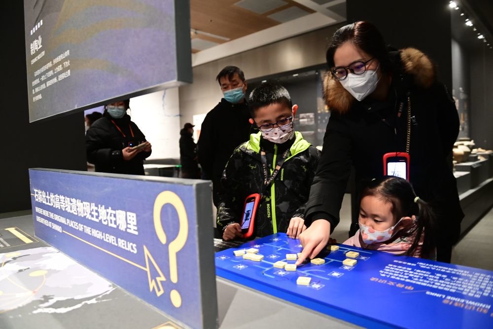 家长带着孩子在陕西考古博物馆体验甲骨文识读互动装置(1月25日摄).