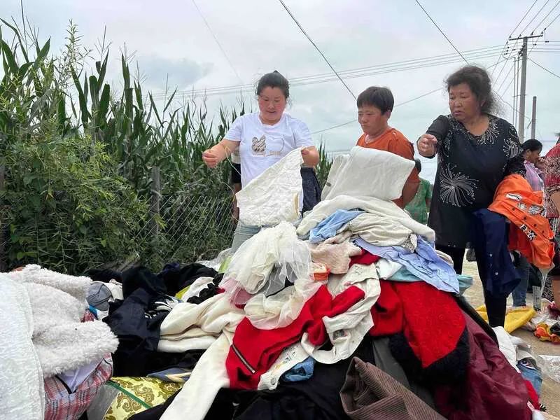 8月7日，一批爱心物资到了三合村，村民挑选衣物。中青报·中青网记者 张均斌/摄