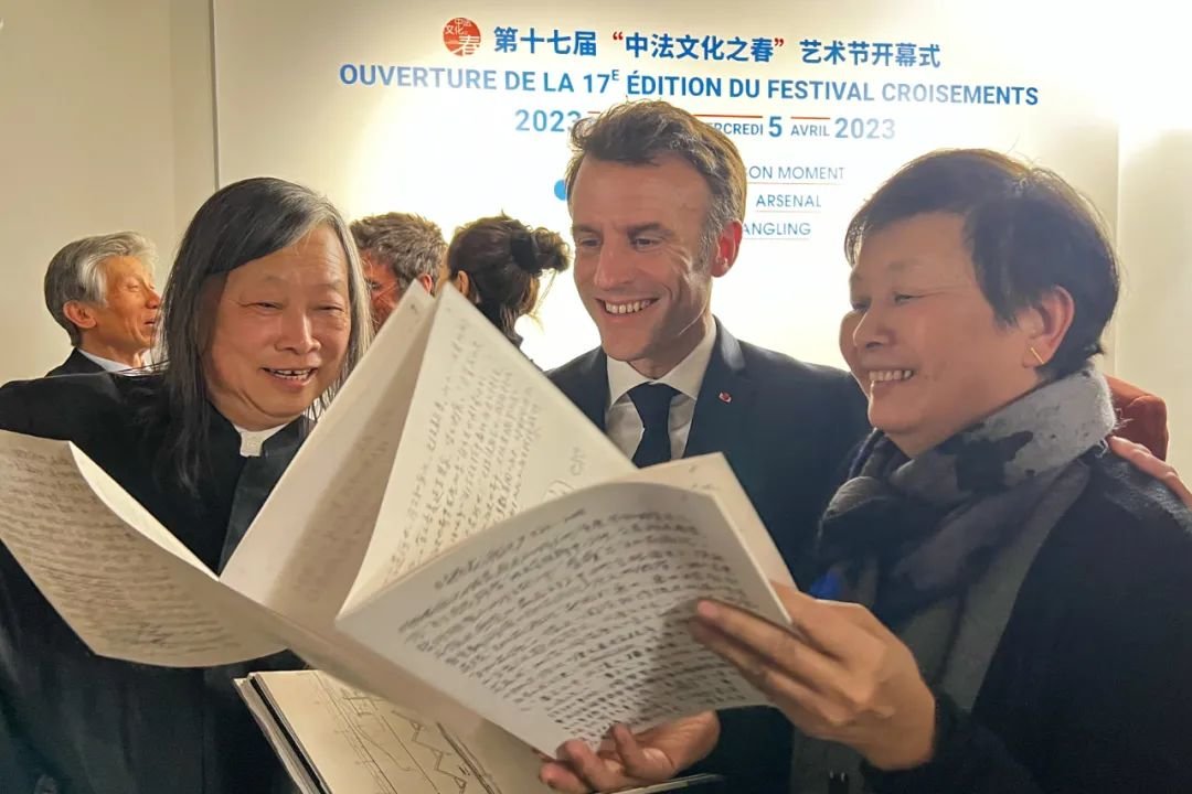 ▲ 2023年,红砖美术馆馆长闫士杰向马克龙赠送艺术家黄永砅“蛇杖”展览画册,图源:红砖美术馆