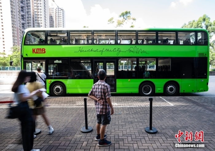 7月27日，香港九龙巴士有限公司在当地向媒体展示即将投入运营的首批电动双层巴士。该巴士采用刀片电池技术，充电两小时可达300公里续航，可实现“零排放”。电动双层巴士车身涂装为标志性的“电光绿”，自7月30日起首先在213M线路(安泰-蓝田站)循环运行。图为途经的市民驻足观看新型巴士。中新社记者 侯宇 摄