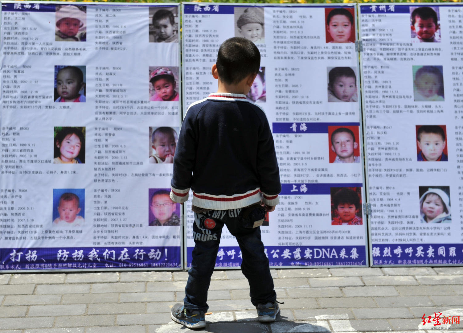 2013年5月2日,福州,“随手公益-寻子之家”全国防拐宣传活动在宝龙城市广场举行,一名路过的儿童看着展板上失踪的同龄孩子的照片。.jpg