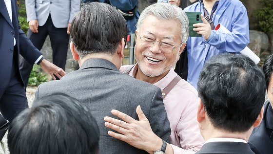 图为今年5月10日，韩国前总统文在寅与访问梁山市平山书店的共同民主党党首李在明打招呼。