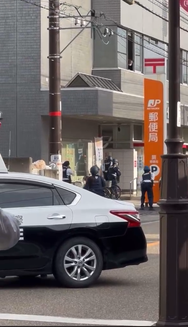 根据日媒报道及社交媒体上流传的视频，拿着盾牌的警察试图查看邮局内情况。
