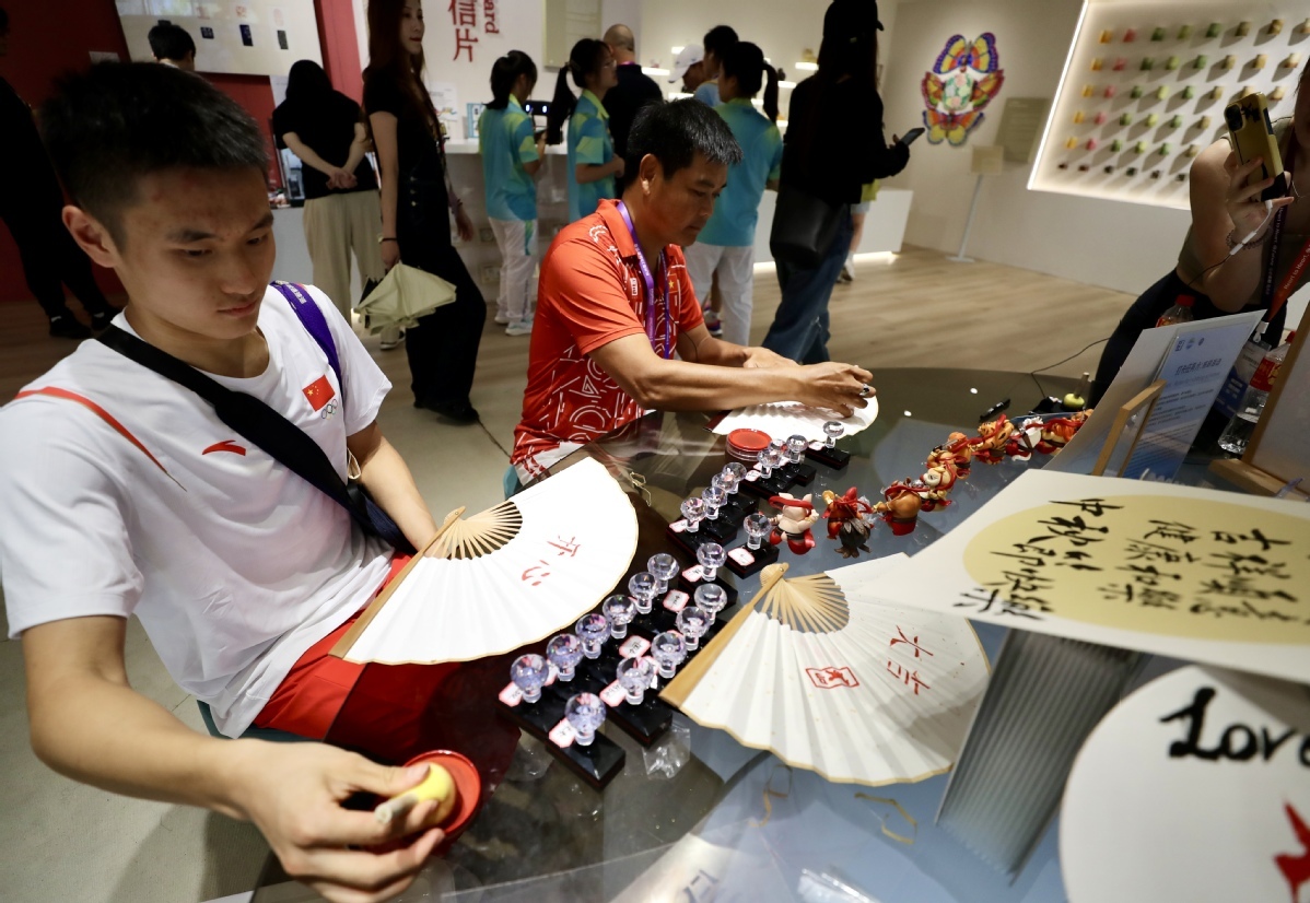 9月29日，中国运动员刘培鑫（左），越南随队官员Quoc Bao Truong在折扇上盖印章。中国日报记者 张威 摄