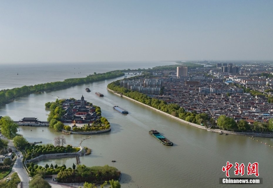 4月16日,航拍京杭大运河畔江苏高邮,运河航运、盂城驿、文游台、汪曾祺纪念馆、清水潭湿地、湖上花海……处处呈现出水乡小城的历史人文气息。高邮依湖傍河,造就了“一城一湖两河三堤”独特景观。图为运输船只穿梭在京杭大运河高邮段水面上。(无人机照片)中新社记者 泱波 摄