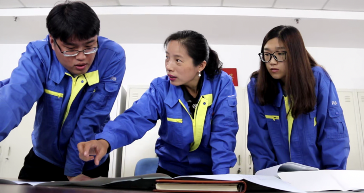姜妍(中)在与同事进行工作交流。 沈鼓集团党委宣传部供图
