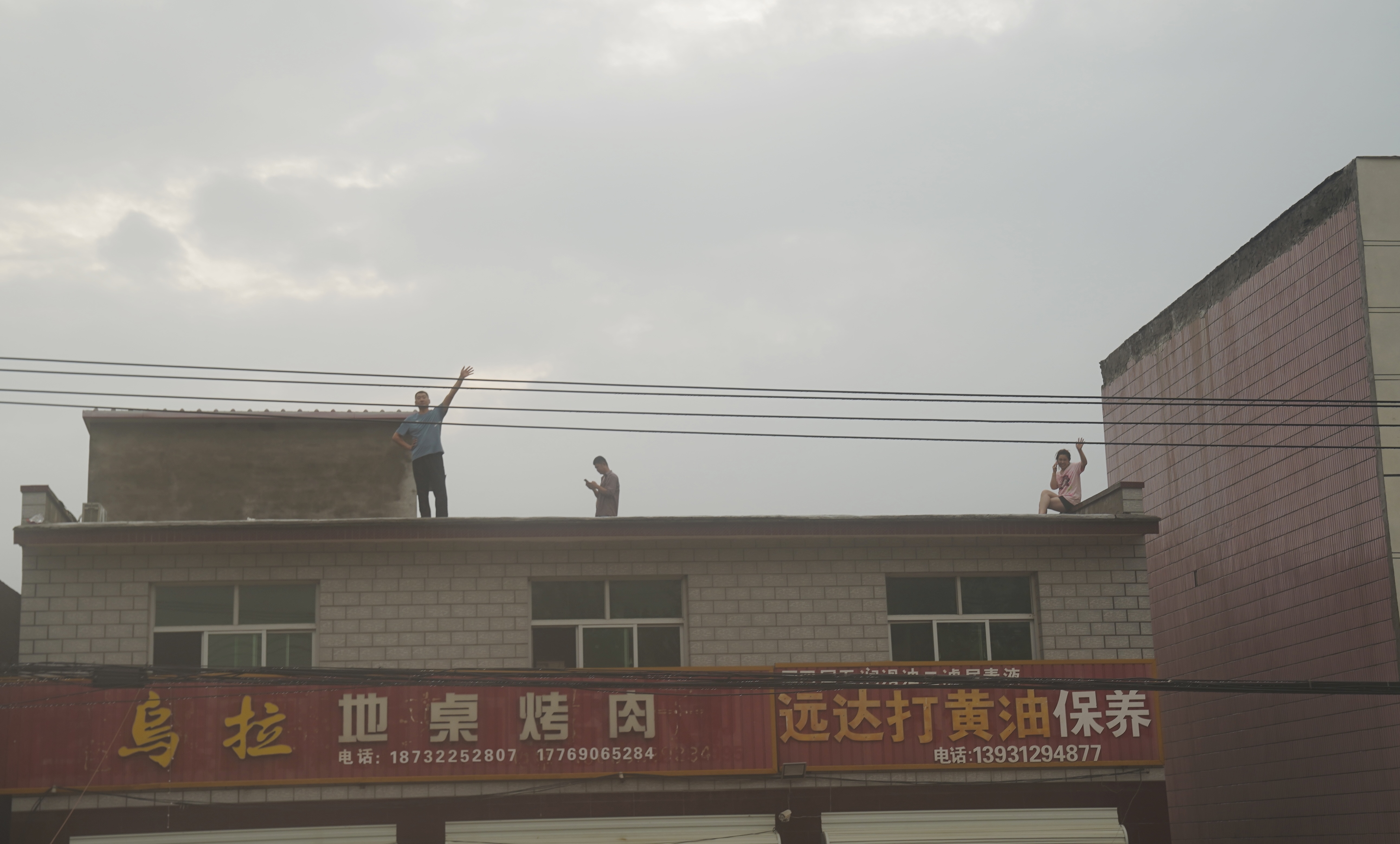 约7月30日晚开始，东仙坡镇下胡良村停电停水，手机没有信号。图为部分村民爬到房顶或在窗户旁大声呼救。