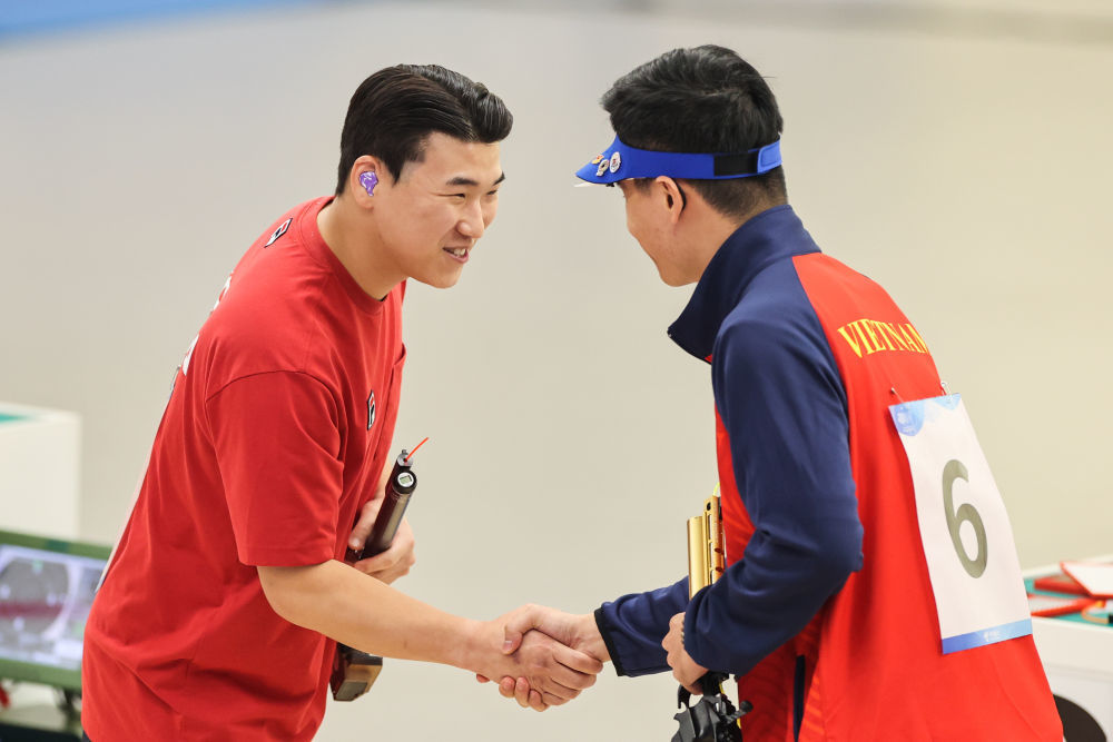 9月28日，韩国选手李元昊（左）与越南选手范光辉在男子10米气手枪个人决赛后握手致意。