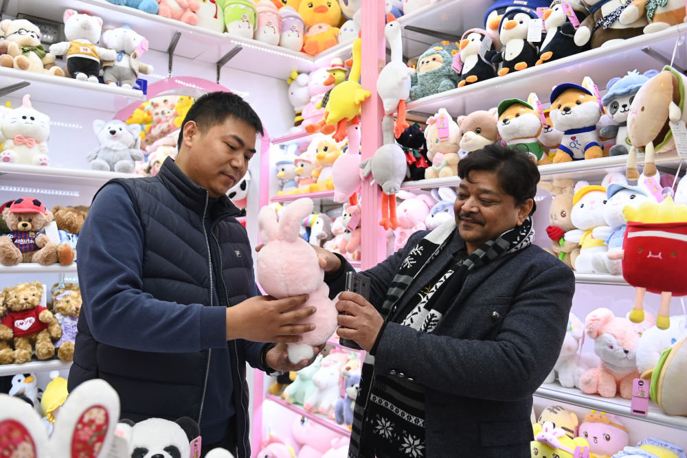 ↑来自印度的客商拉贾（右）在义乌国际商贸城的一家玩具店铺内选购（2月2日摄）。