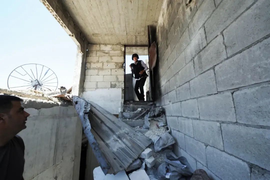▲穿着防弹衣的焦翔在叙利亚一栋破损的楼内采访，差点中弹