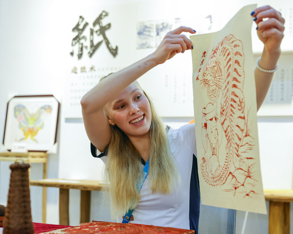8月3日，在成都大运村的互动体验中心，芬兰运动员杰茜卡·卡哈拉展示自己制作的夹江年画。新华社记者 沈伯韩 摄