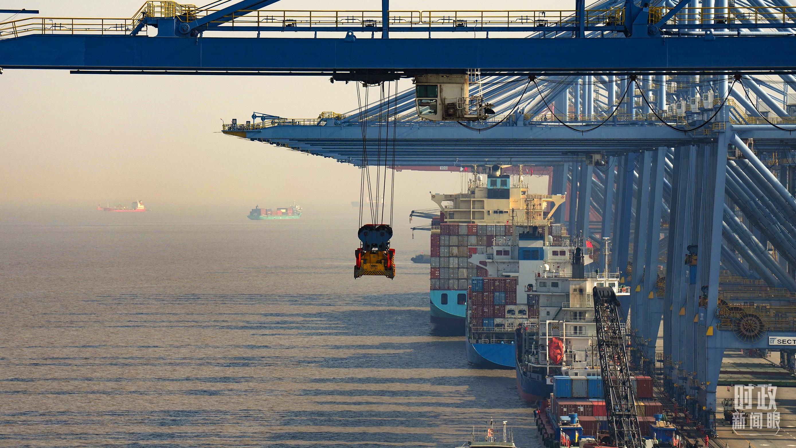 △上港集箱外高桥码头,巨型塔吊正在吊装集装箱货柜。(总台国广记者李晋拍摄)