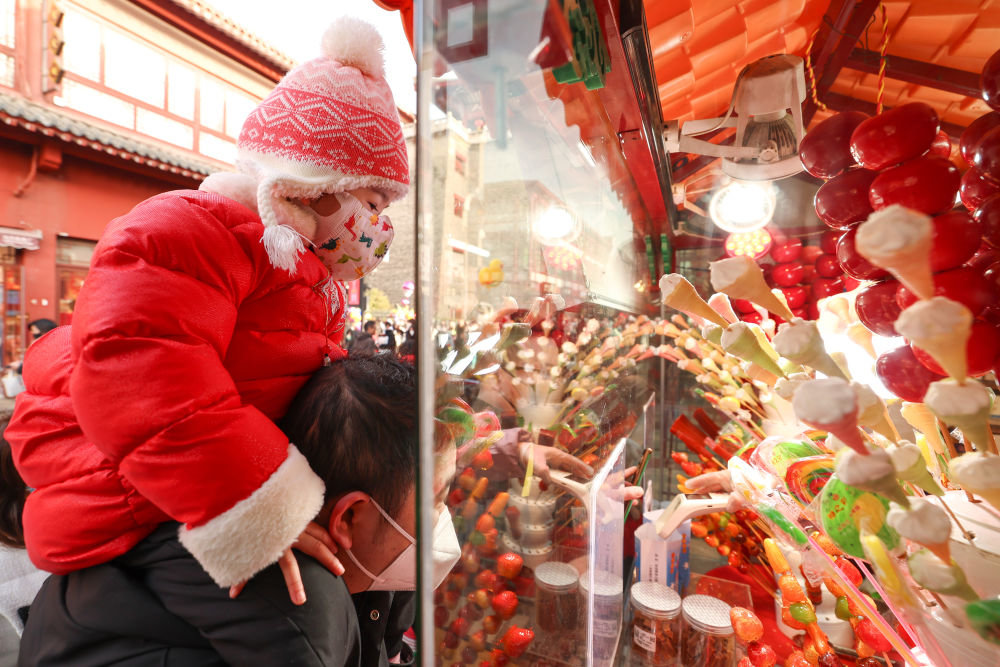 ↑1月24日，家长带着小朋友在湖北襄阳古城北街选购糖葫芦。新华社发（杨东 摄）