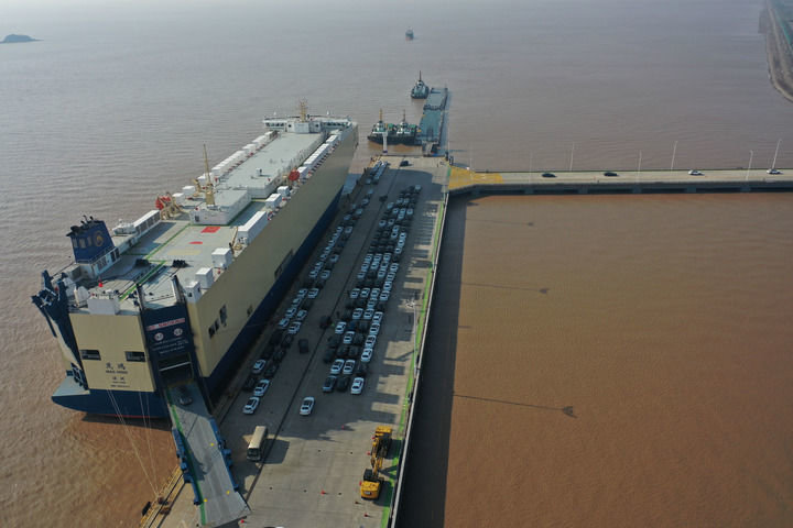 一艘滚装船停靠在浙江宁波舟山港梅东码头，装运的汽车从船内驶出（2022年12月13日摄，无人机照片）。新华社记者 黄宗治 摄