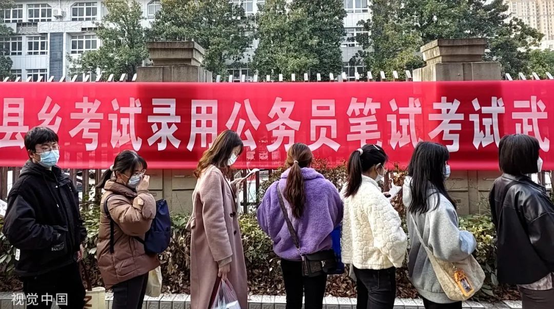 2023年2月25日，武汉技师学院考点，参加公务员考试的考生排队边复习边等进入考点/图源：视觉中国